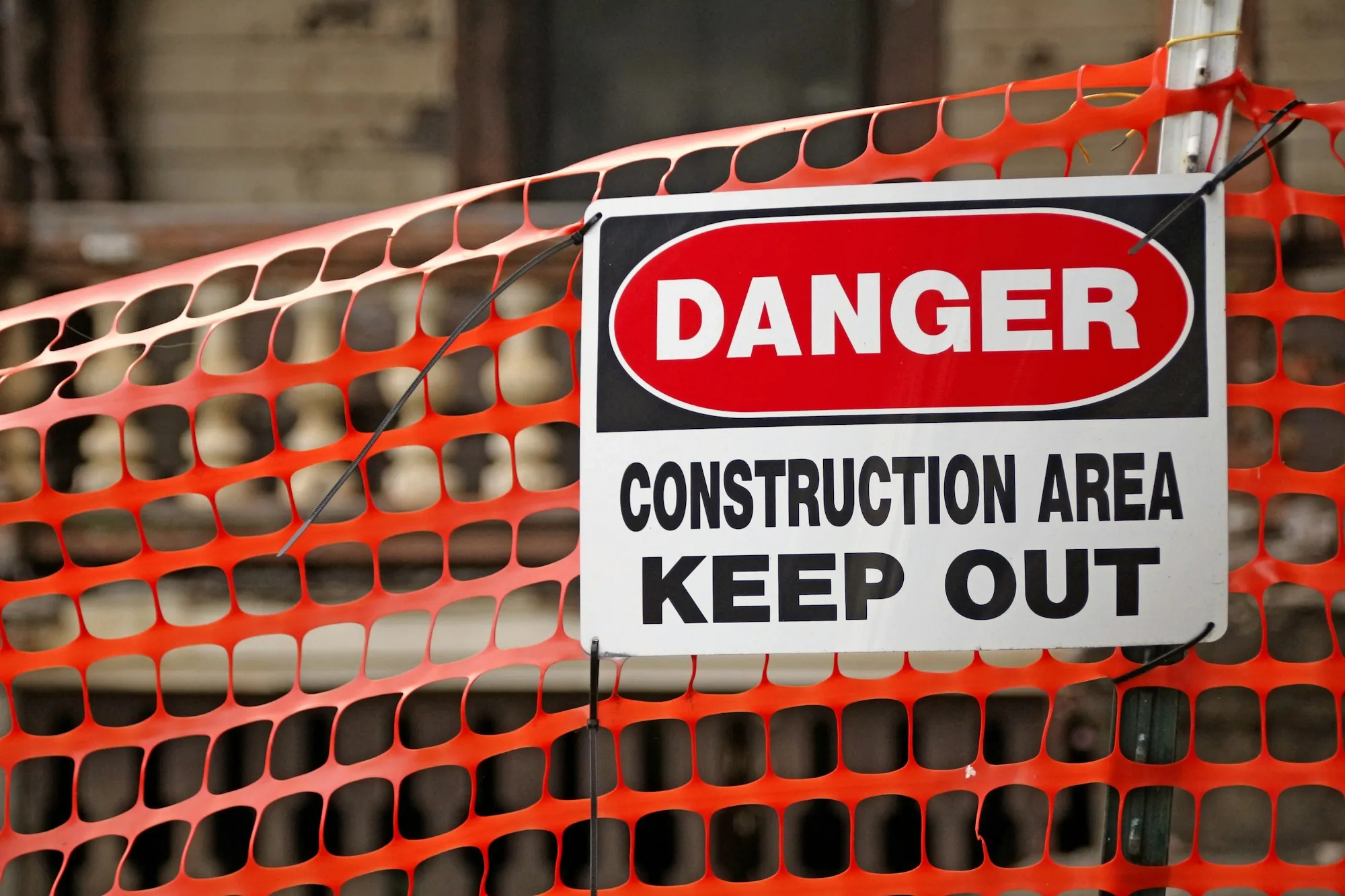 Danger construction area keep out sign on orange fencing